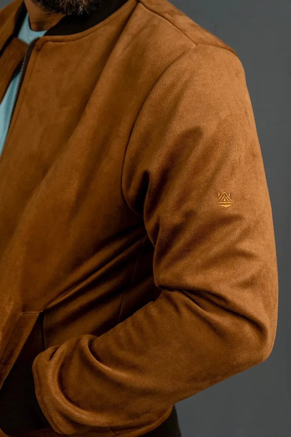 Detalle logo bordado en manga de chaqueta bomber café Luck & Load para hombre — zoom textura gamuza sintética