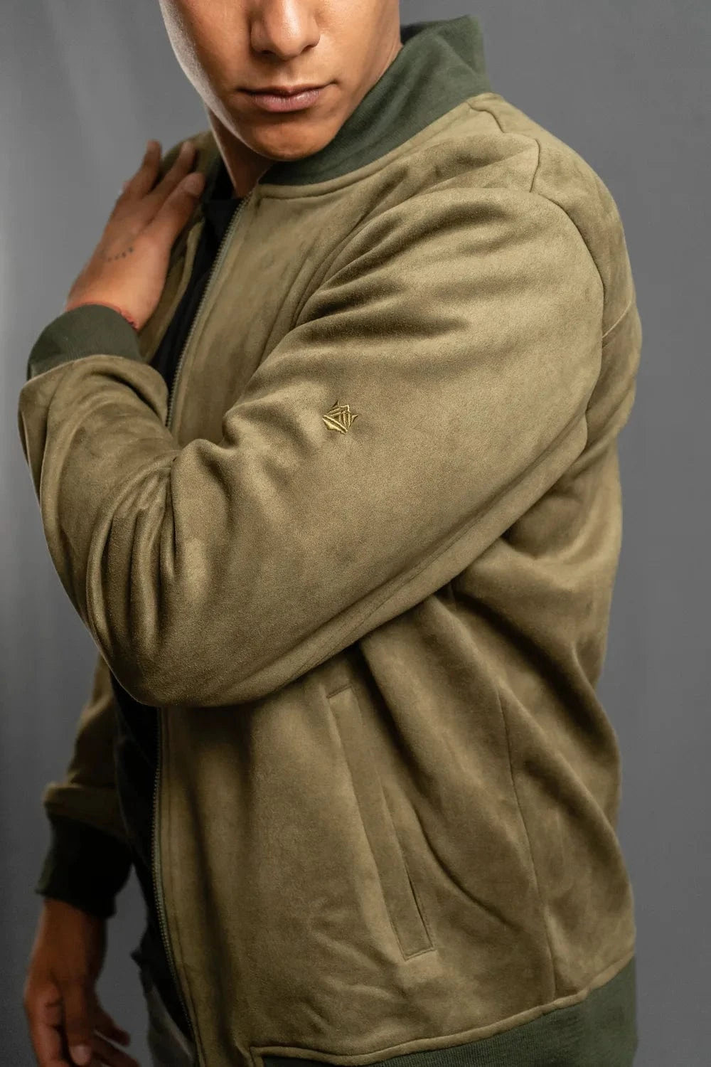 Detalle logo en manga de chaqueta bomber verde oliva Luck & Load para hombre — primer plano tejido gamuza