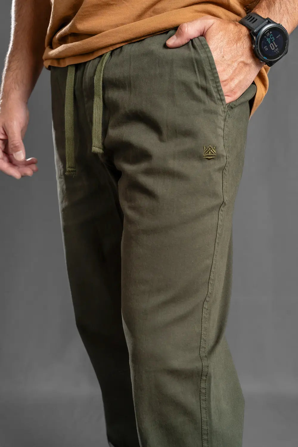 Close-up del bolsillo y cordón del pantalón jogger verde militar, ideal para outfit urbano y viajes cómodos