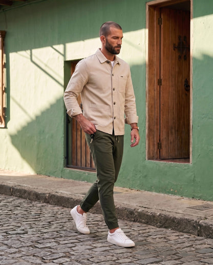 Jogger hombre verde militar en drill premium, look urbano caminando en calle empedrada | Luck & Load Colombia