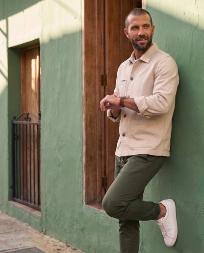 Jogger hombre verde militar en drill premium, estilo casual apoyado en pared urbana | Luck & Load Colombia