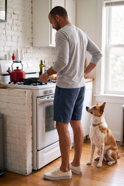 Hombre cocinando en casa con bermuda de descanso azul naval; estilo de vida Luck & Load.