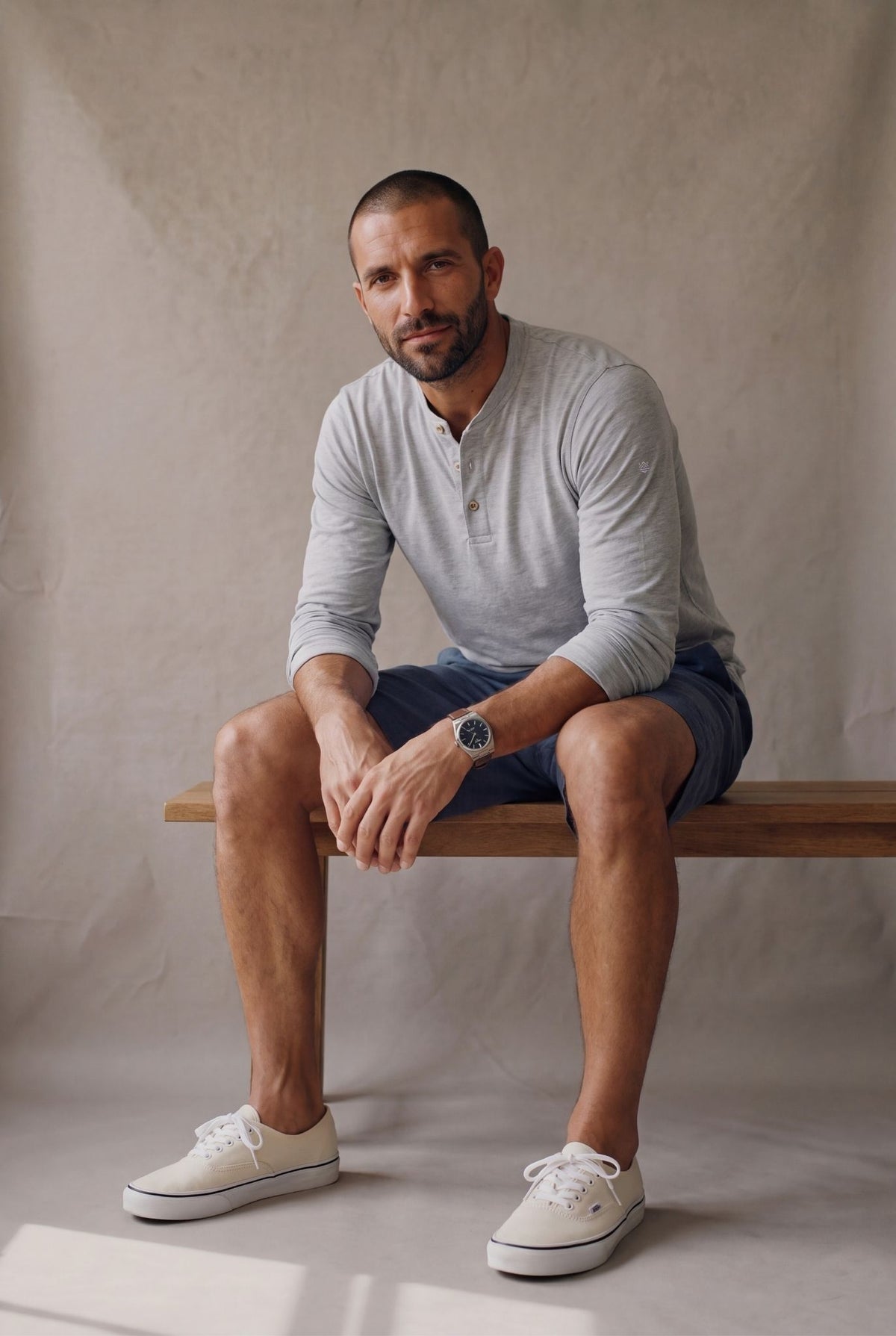 Hombre sentado con bermuda de descanso azul naval y henley gris jaspe de Luck & Load.