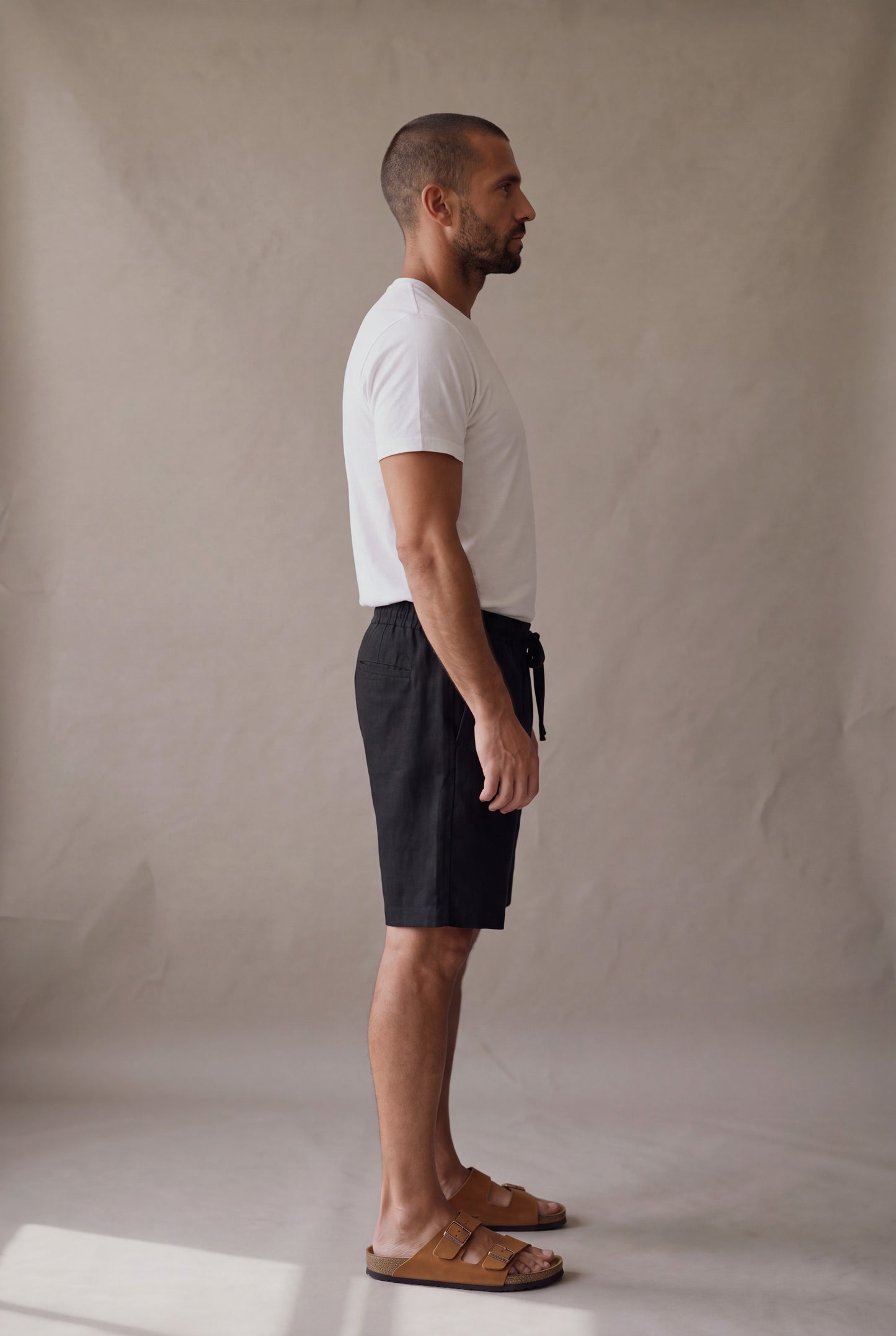 Bermuda de descanso negra para hombre, vista lateral; bolsillo lateral y largo arriba de la rodilla. Luck & Load.