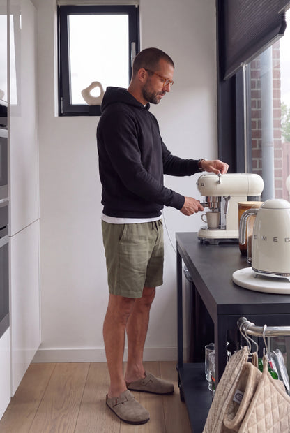 Hombre preparando cafe con bermuda de descanso verde militar; estilo de vida Luck & Load.