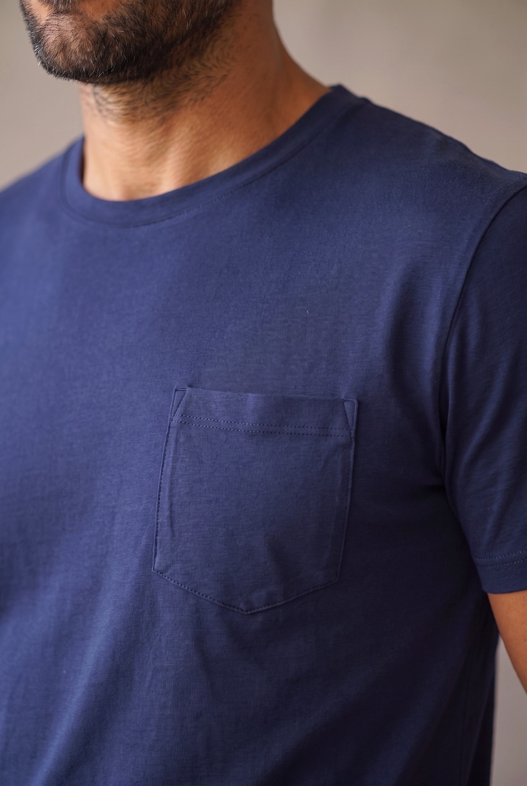 Detalle del bolsillo de pecho pentagonal de la camiseta azul marino de cuello redondo en algodón peruano