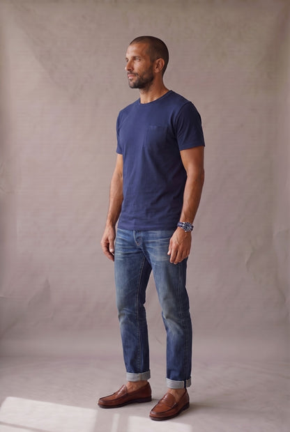 Hombre de perfil con camiseta azul marino de bolsillo en algodón peruano, en estudio neutro