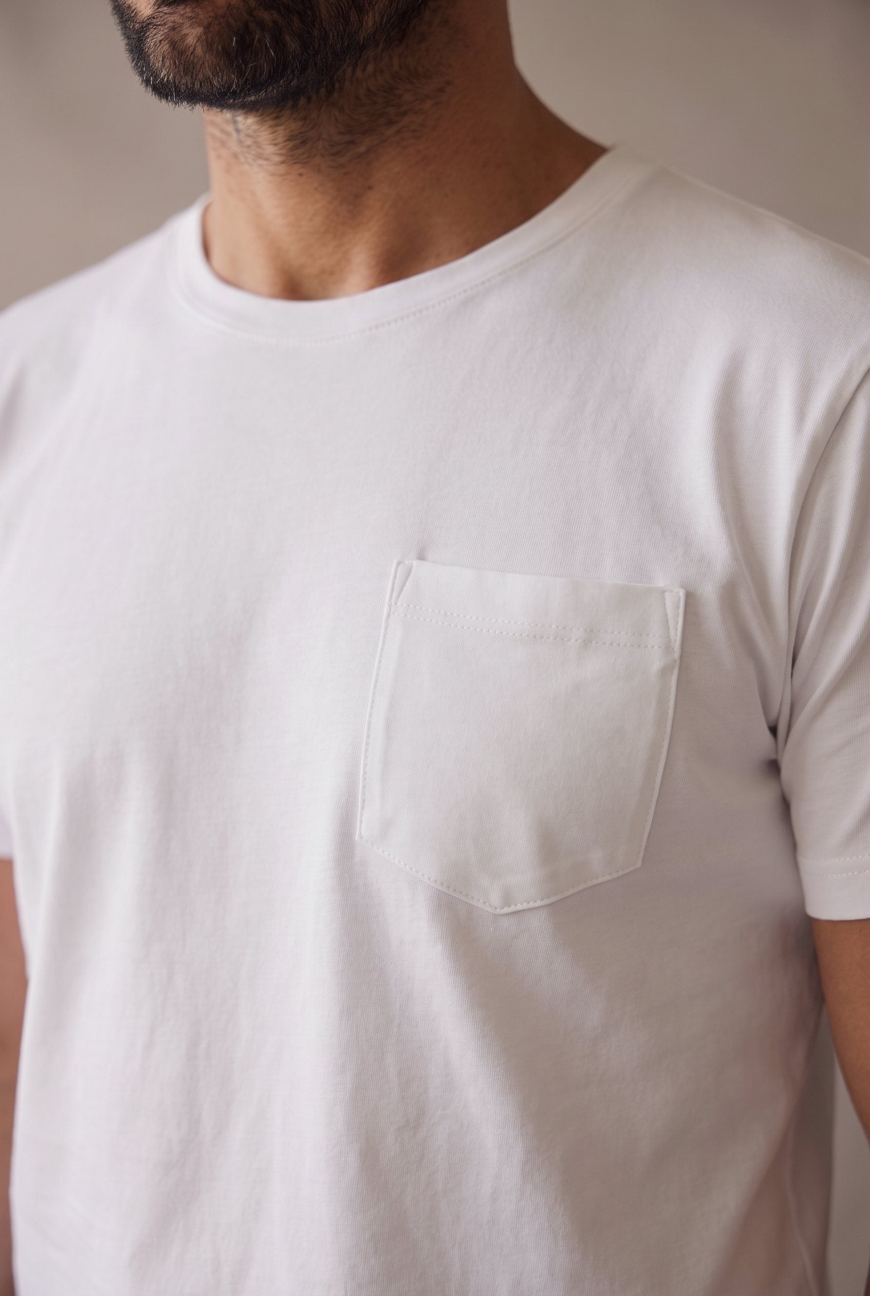 Detalle del bolsillo de pecho pentagonal de la camiseta blanca de cuello redondo en algodón peruano