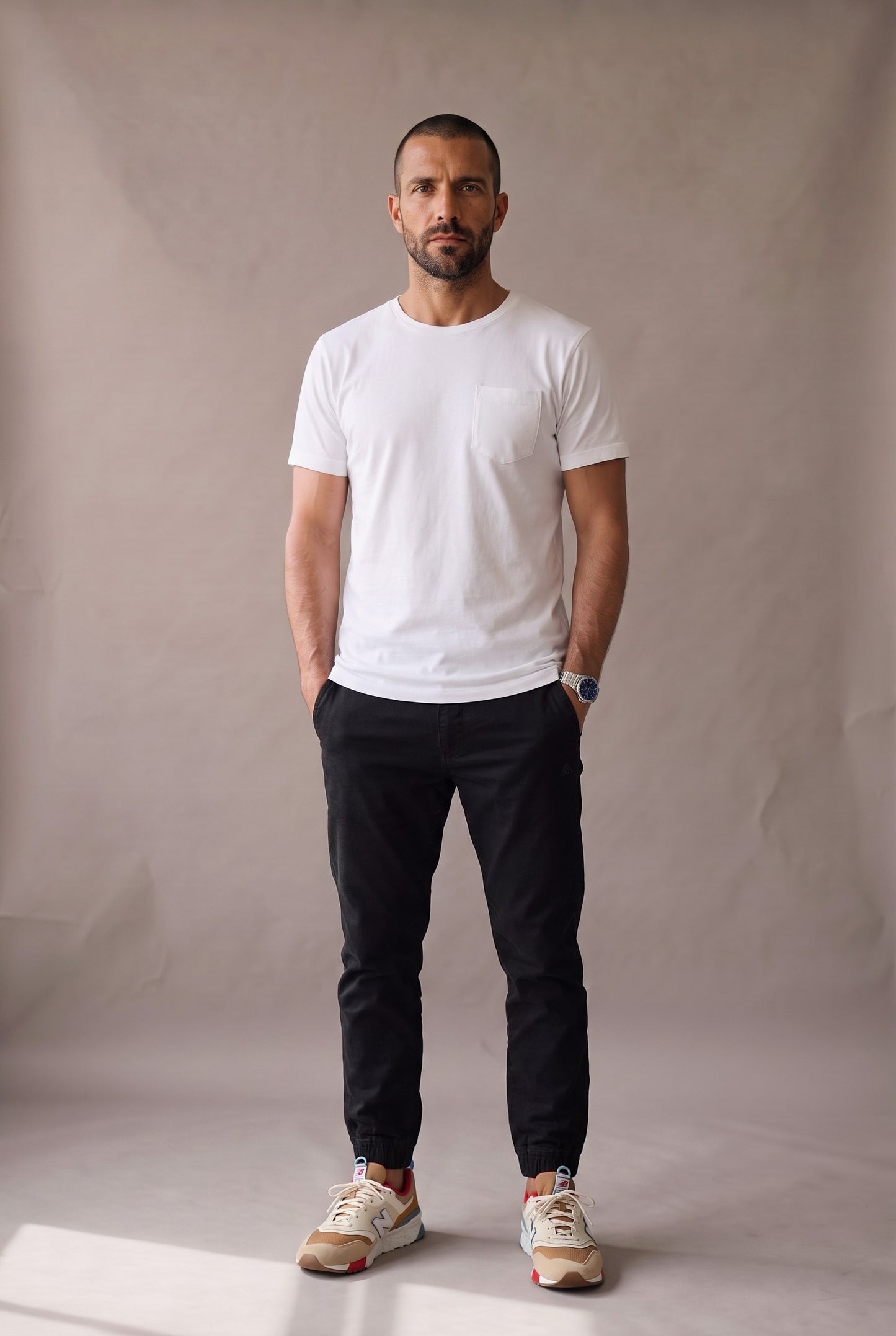 Hombre en camiseta blanca de cuello redondo con bolsillo en algodón peruano, jogger negro y tenis claros