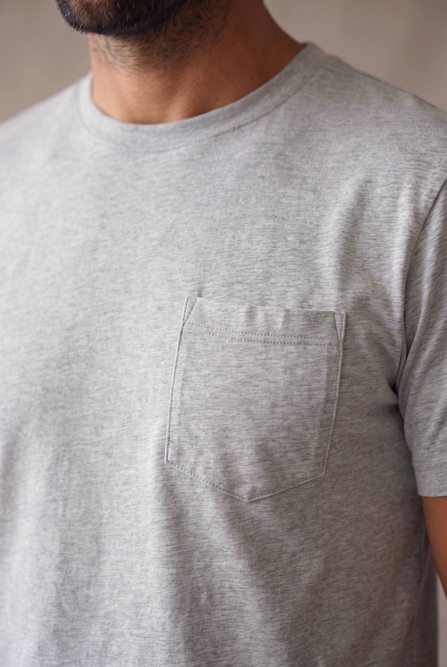 Detalle del bolsillo de pecho pentagonal, el cuello y la tela de la camiseta gris de cuello redondo en algodon peruano.