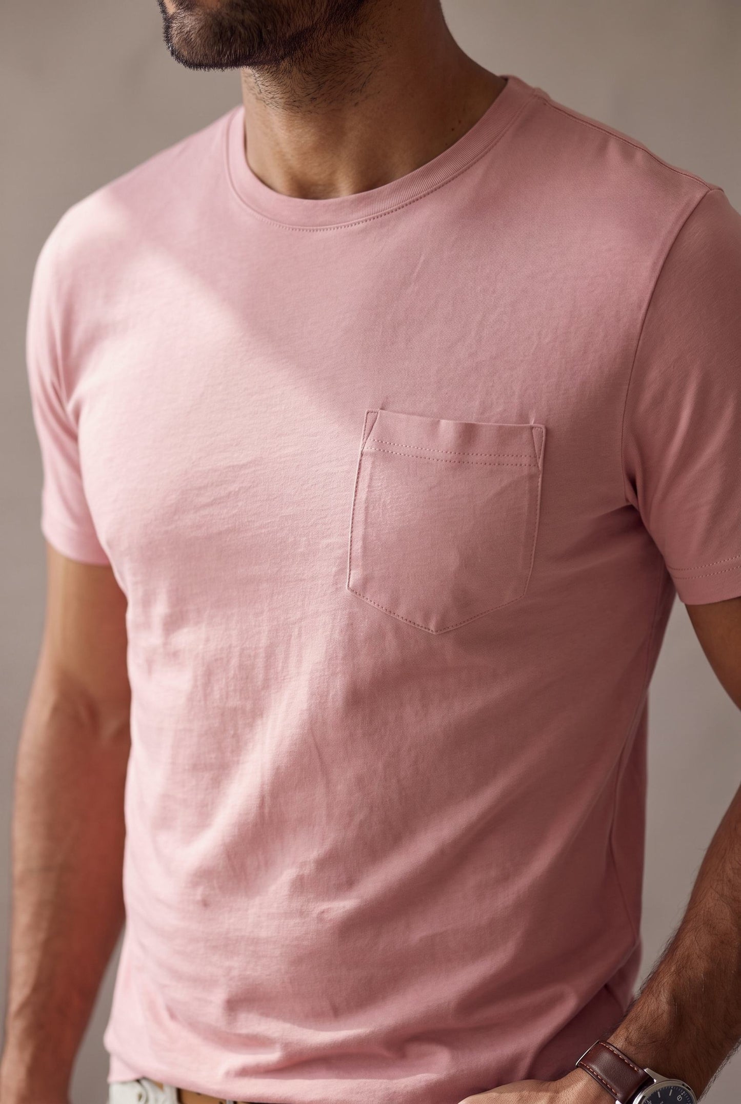 Detalle del bolsillo de pecho pentagonal, el cuello y la tela de la camiseta rosada de cuello redondo en algodon peruano.