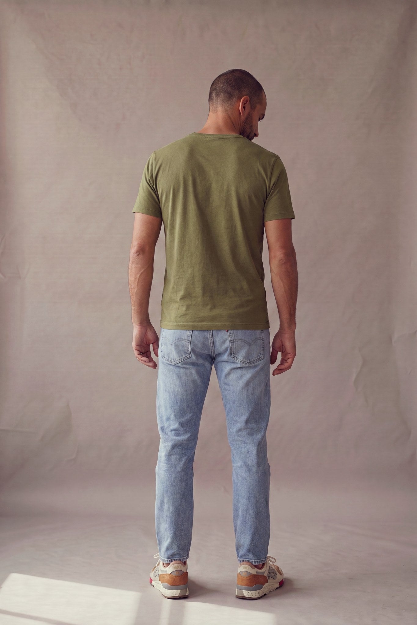 Vista de espalda de la camiseta verde militar de cuello redondo con bolsillo en algodon peruano, corte recto.