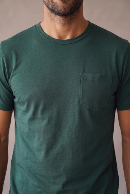 Detalle del bolsillo de pecho pentagonal, el cuello y la tela de la camiseta verde pino de cuello redondo en algodon peruano.