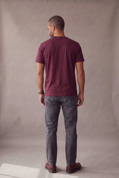 Vista de espalda de la camiseta de cuello redondo vinotinto con bolsillo de Luck and Load, con jeans gris oscuro; foto de catalogo en estudio.