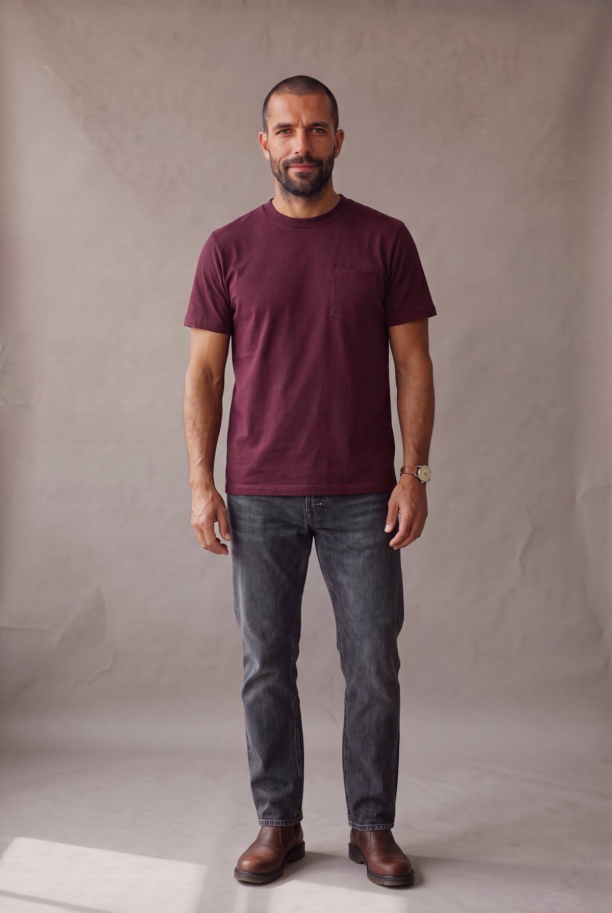 Hombre de frente vistiendo la camiseta de cuello redondo vinotinto con bolsillo de Luck and Load, con jeans gris oscuro; foto de catalogo en estudio.