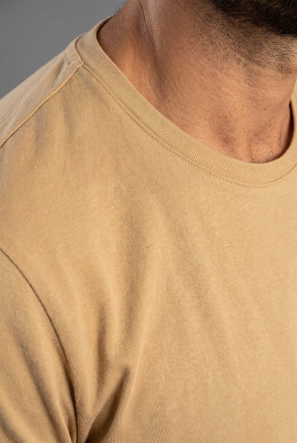Detalle del cuello redondo y la costura de hombro de la camiseta beige de Luck & Load en algodón mate