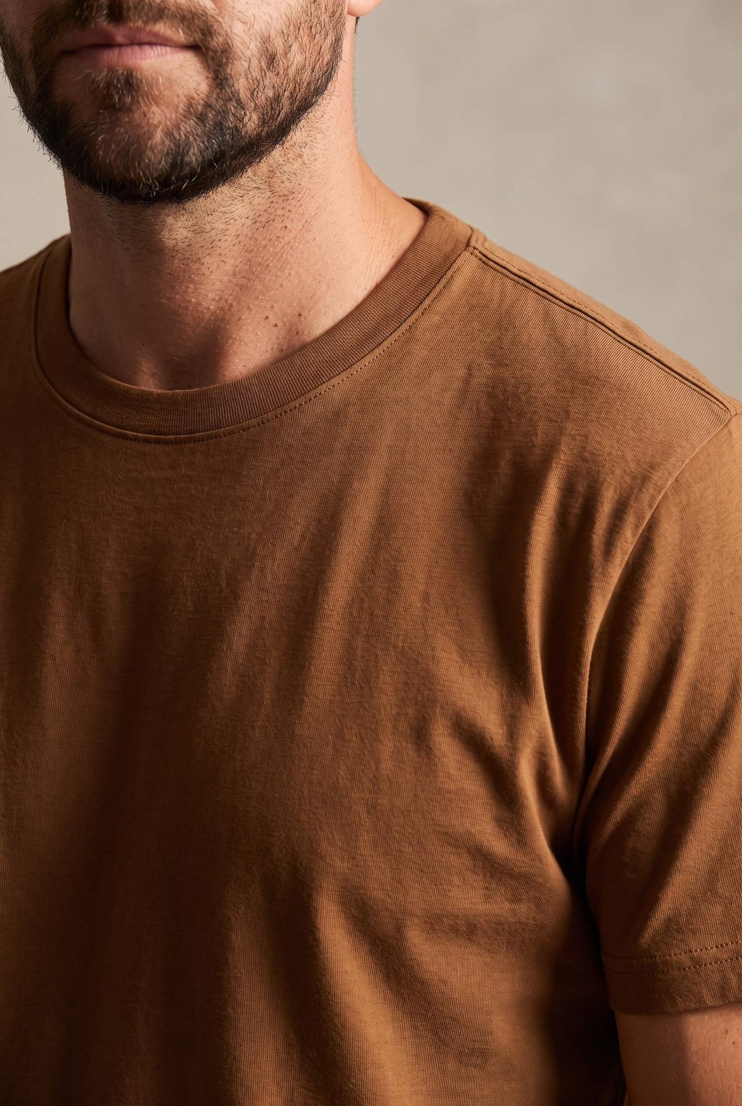 Detalle del cuello redondo y la costura de hombro de la camiseta café de Luck & Load en algodón mate