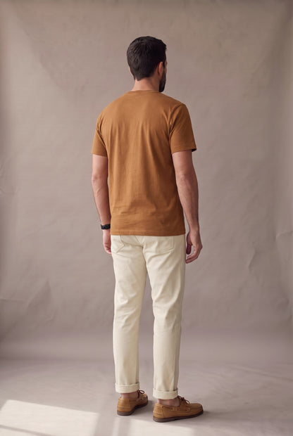 Vista de espalda de la camiseta café de cuello redondo de Luck & Load, con el largo y la caída del algodón sobre un hombre de pie