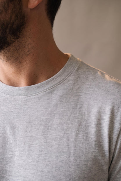 Detalle del cuello redondo de la camiseta gris de hombre, ribete plano y limpio visto de perfil