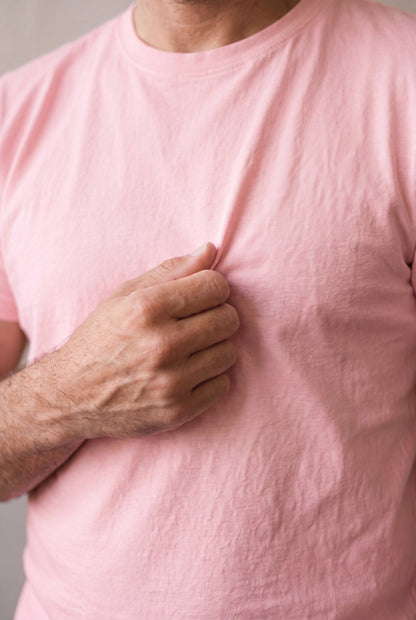 Primer plano del tejido de algodón peruano de la camiseta rosa palo de Luck & Load sostenido entre los dedos.