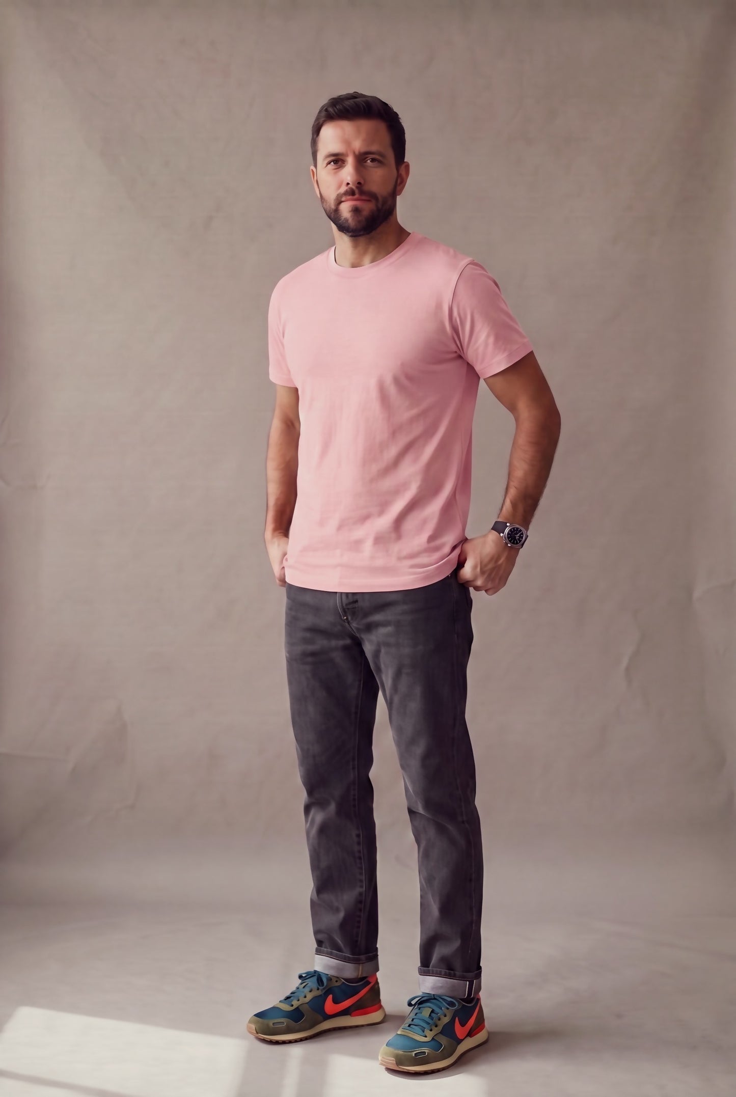 Hombre de pie con camiseta rosa palo de cuello redondo sin bolsillo de Luck & Load, con jean gris y tenis vintage.