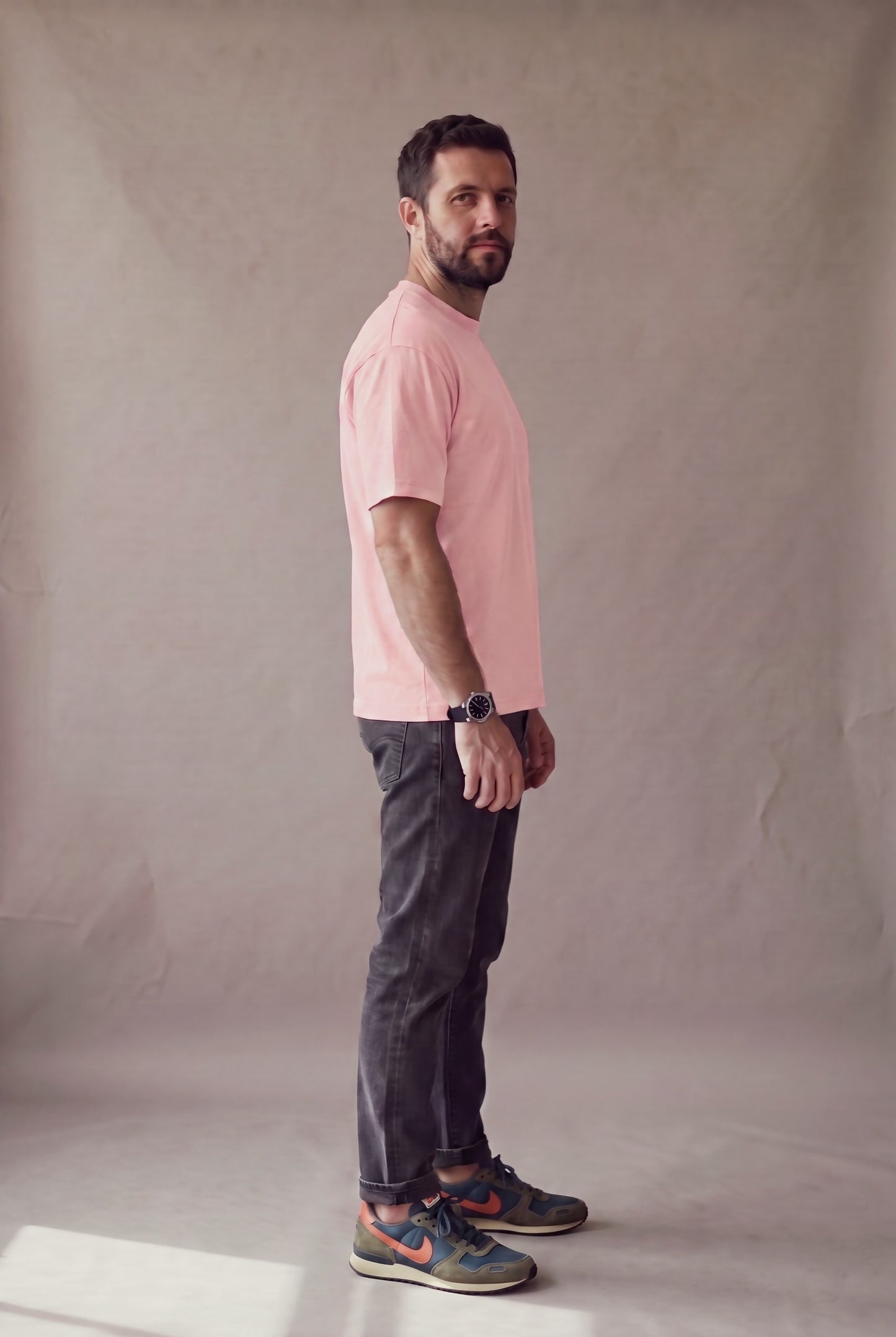 Vista lateral de la camiseta rosa palo de cuello redondo de Luck & Load sobre un hombre de pie.