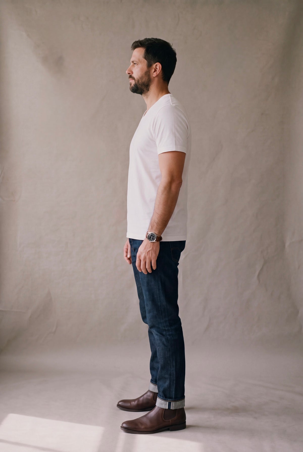 Vista lateral de la camiseta cuello en V blanca Luck and Load con jean indigo y bota chelsea cafe