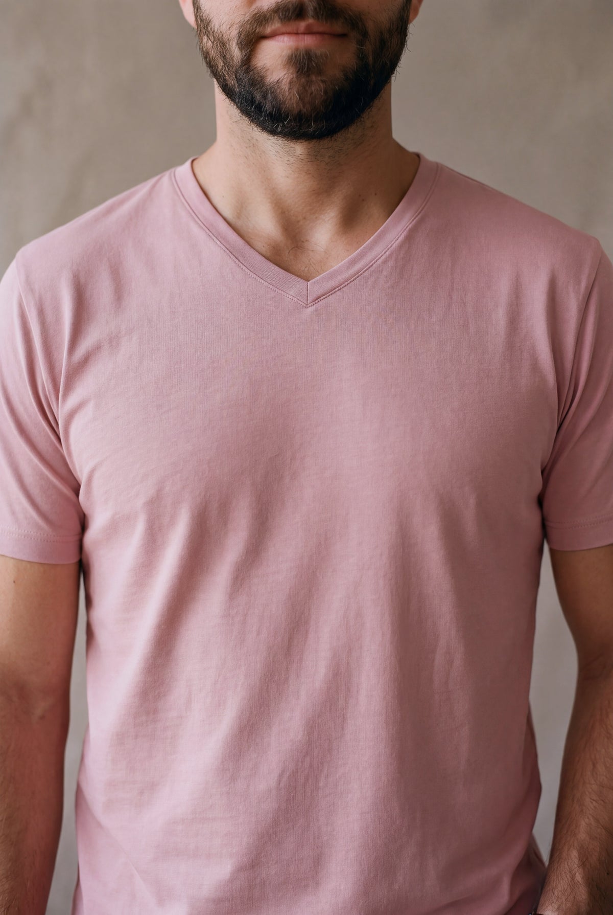 Detalle del cuello en V de la camiseta rosa palo Luck and Load, banda plana y pico en inglete
