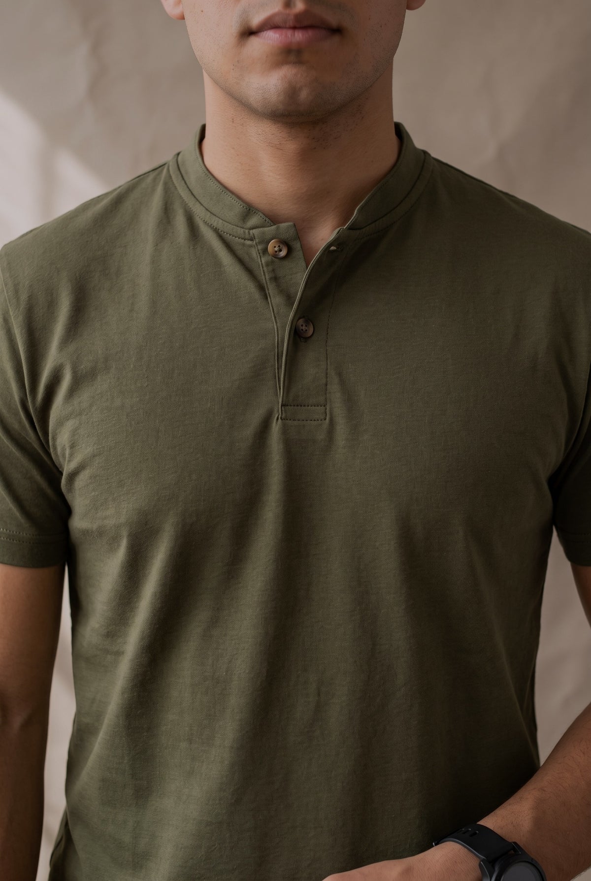 Detalle de la cartera de la camiseta verde militar Luck & Load, con pespunte tonal y dos botones de corozo café
