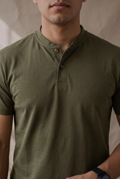 Detalle de la cartera de la camiseta verde militar Luck & Load, con pespunte tonal y dos botones de corozo café