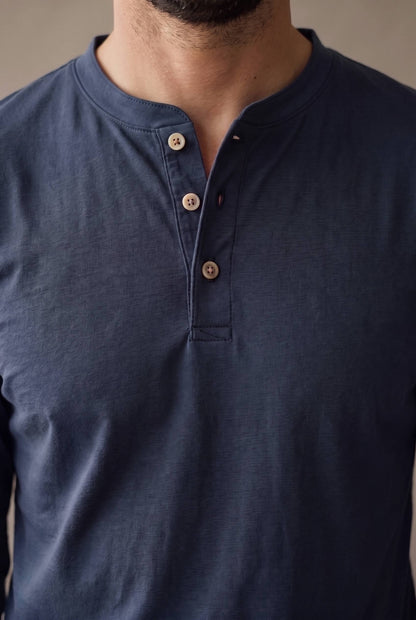 Detalle de la cartera de tres botones de corozo y las costuras de la camiseta henley azul marino.