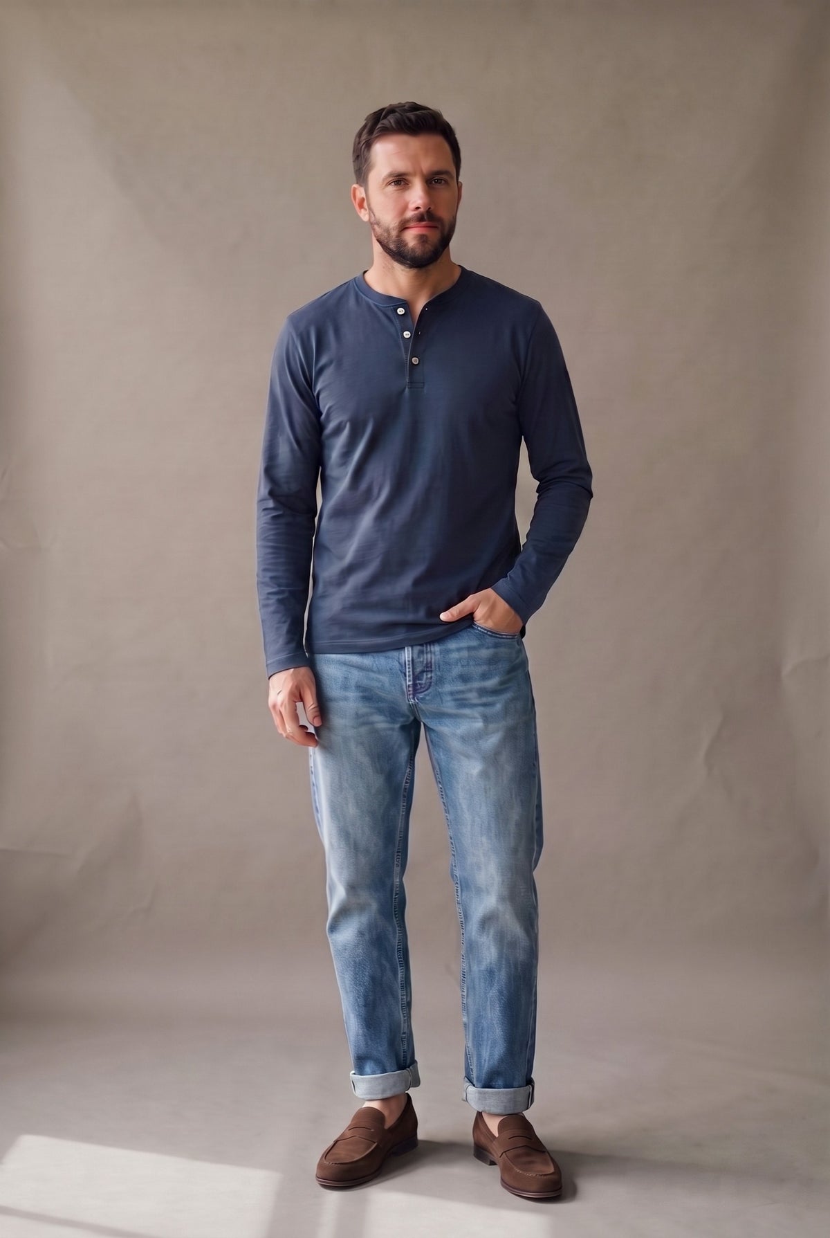 Hombre de frente con camiseta henley manga larga azul marino de tres botones, jean y mocasines café.