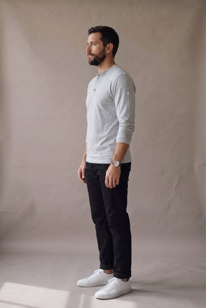 Vista lateral de la camiseta henley manga larga gris jaspe con puño liso y caída limpia.