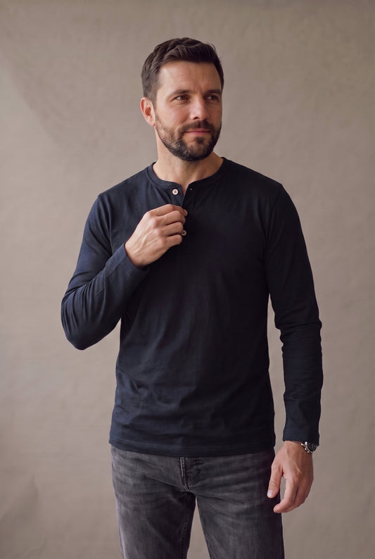Medio cuerpo de la camiseta henley negra con la cartera de tres botones de corozo al centro.