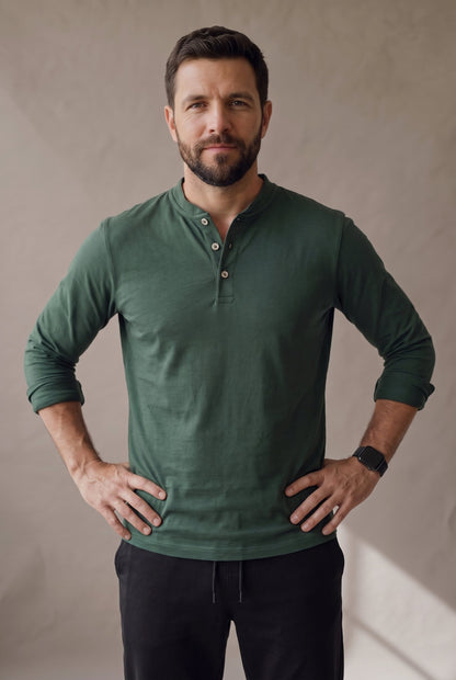 Medio cuerpo de la camiseta henley verde pino con la cartera de tres botones de corozo y el reloj a la vista
