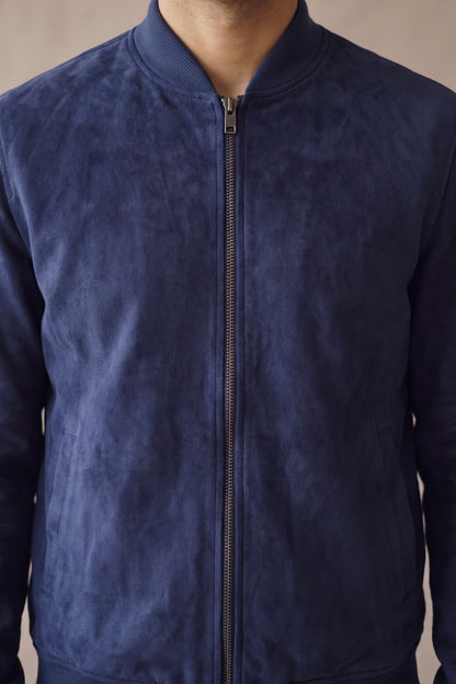 Detalle del cuello tejido, el cierre metálico y la gamuza de la bomber azul de Luck & Load.