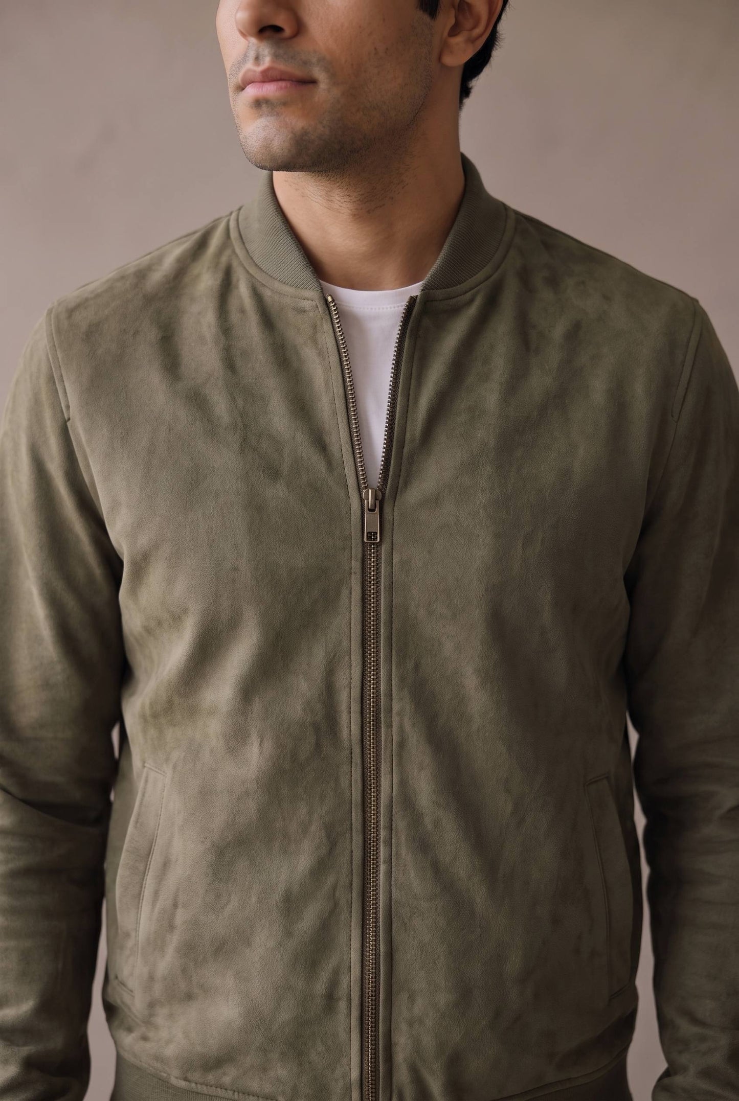 Detalle del cuello tejido, el cierre metálico y la gamuza de la bomber verde militar de Luck & Load.