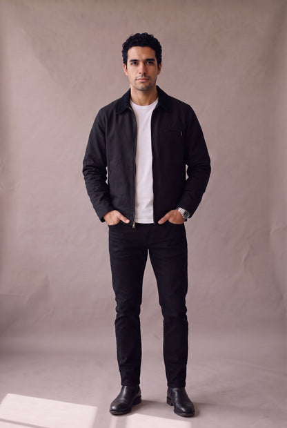 Chaqueta Detroit negra de cuello de pana de Luck and Load, vista frontal; hombre con camiseta blanca, jean negro recto y botin Chelsea negro. Colombia