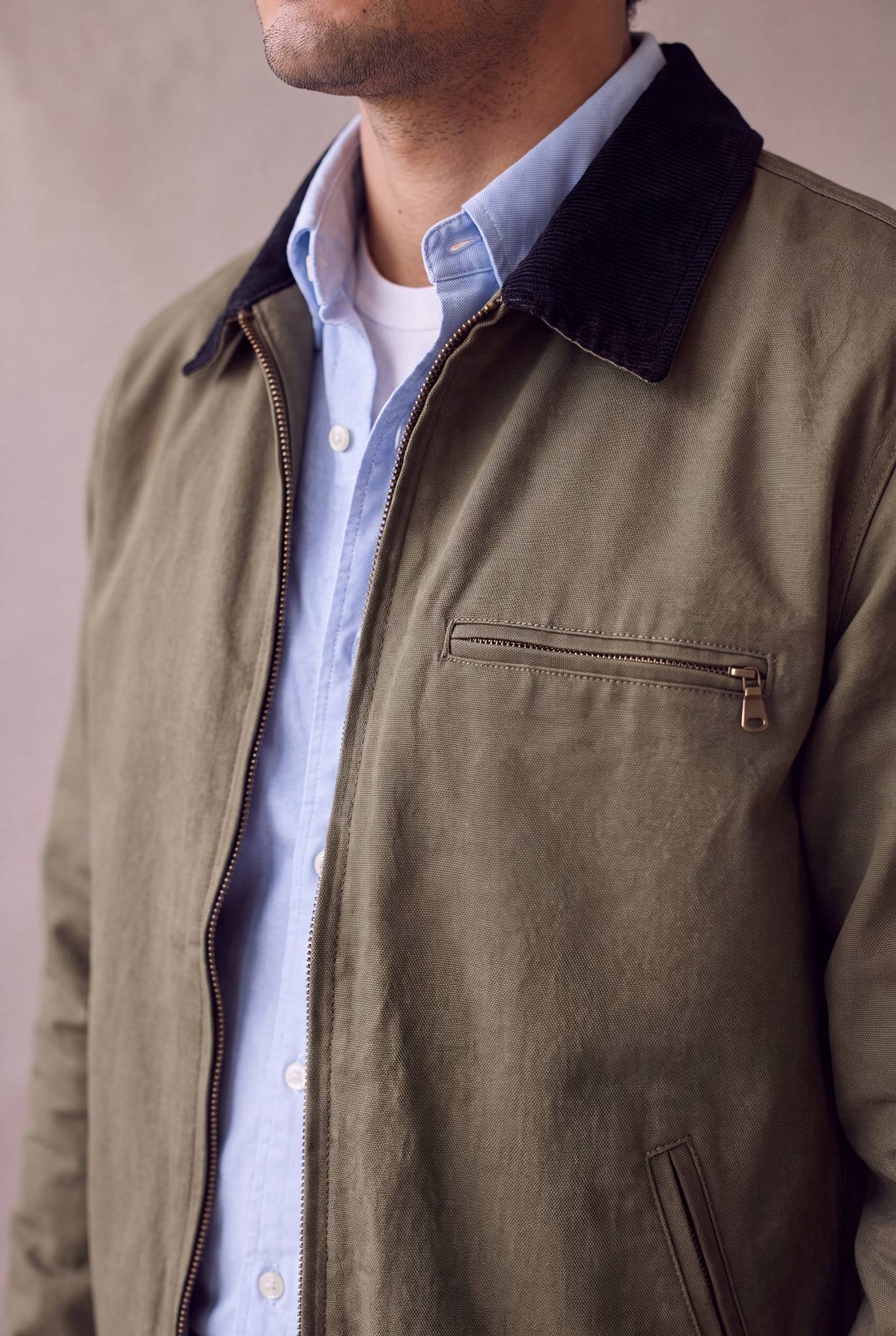 Detalle de la chaqueta Detroit color verde oliva militar de Luck and Load: cuello de pana negro, cierre central de laton y camisa oxford celeste en capas. Colombia