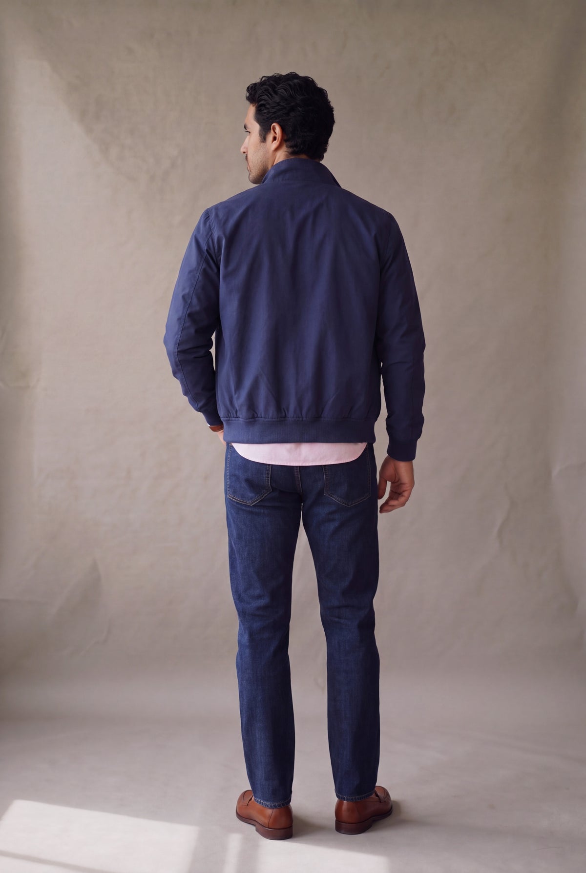 Vista de espalda de la chaqueta Harrington azul marino de Luck & Load, con el corte recto y el largo a la cadera.
