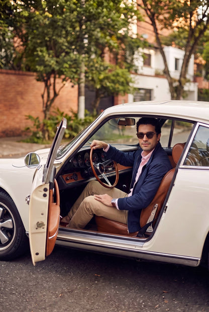 Hombre con la chaqueta Harrington azul marino de Luck & Load junto a un Porsche 911 clásico en El Poblado.
