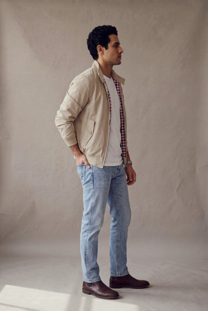 Vista lateral de la chaqueta Harrington beige de Luck & Load sobre camiseta blanca y jean claro.