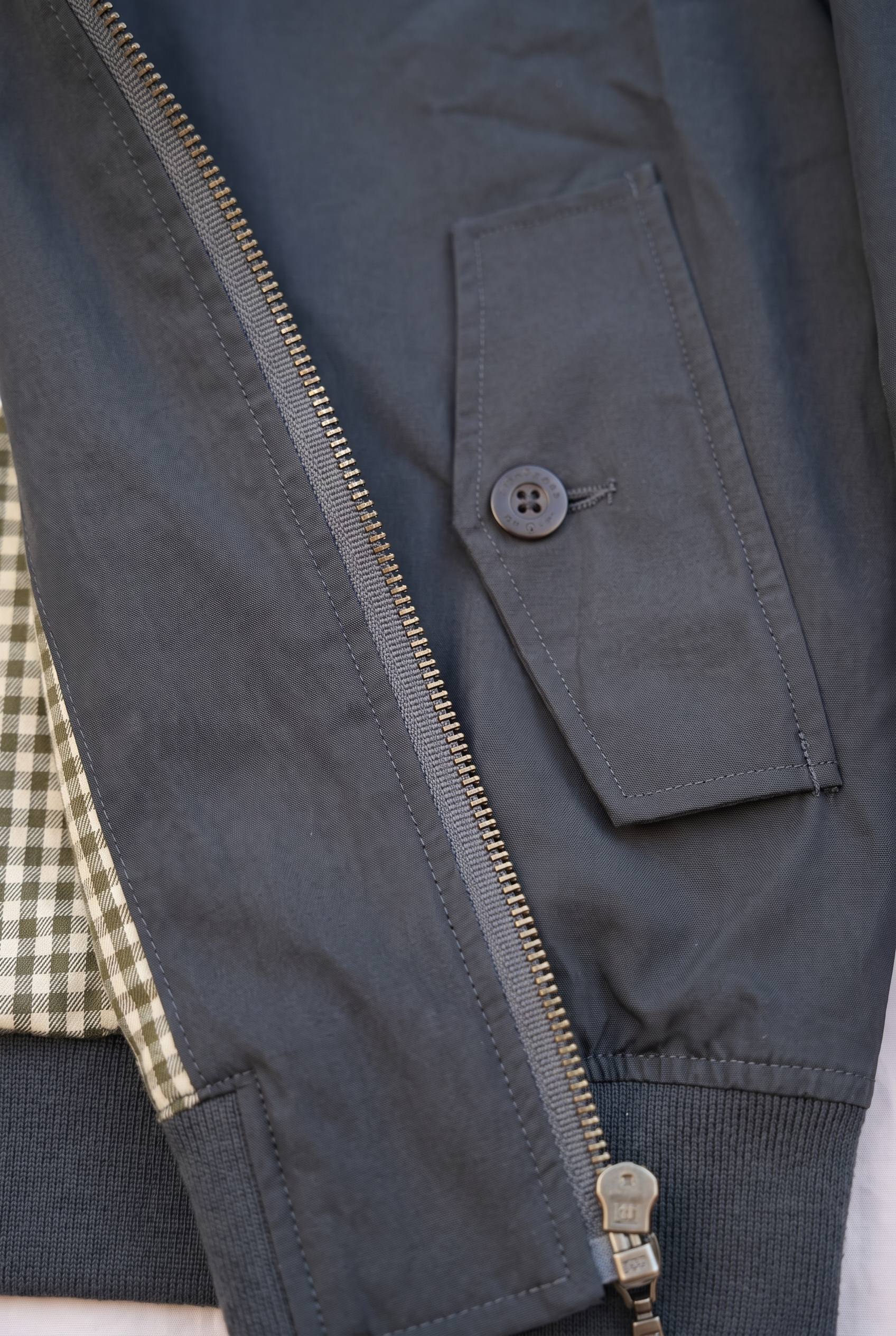 Primer plano de los bolsillos y el tejido de la chaqueta Harrington negra de Luck & Load.
