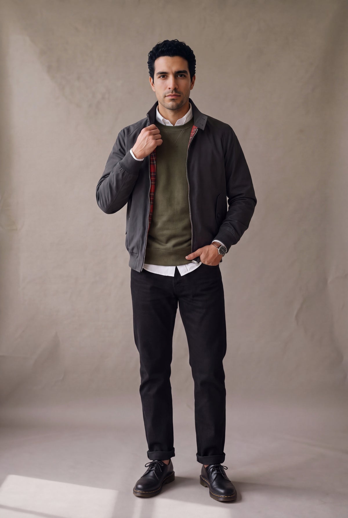 Chaqueta Harrington negra para hombre de Luck & Load, abierta sobre buzo verde oliva y camisa blanca, con botas Dr. Martens.