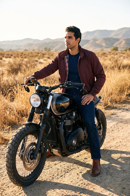 Hombre sobre una moto clásica en una carretera abierta con la chaqueta Harrington vinotinto de Luck & Load.