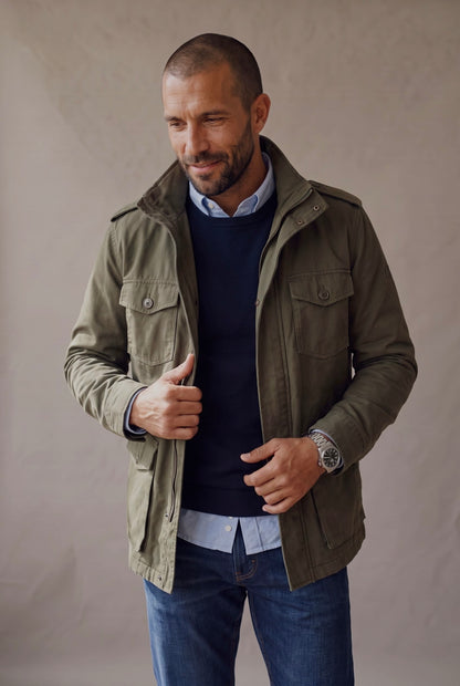 Chaqueta militar para hombre en verde oliva con sueter azul, plano medio cuerpo casual, Luck and Load