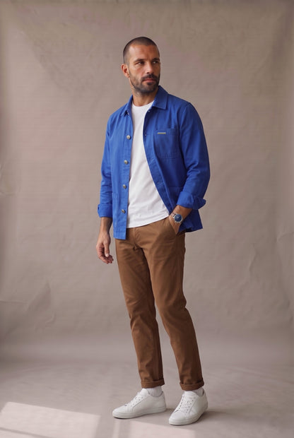 Chaqueta obrera azul rey para hombre de Luck & Load, vista lateral de cuerpo entero con las mangas arremangadas.