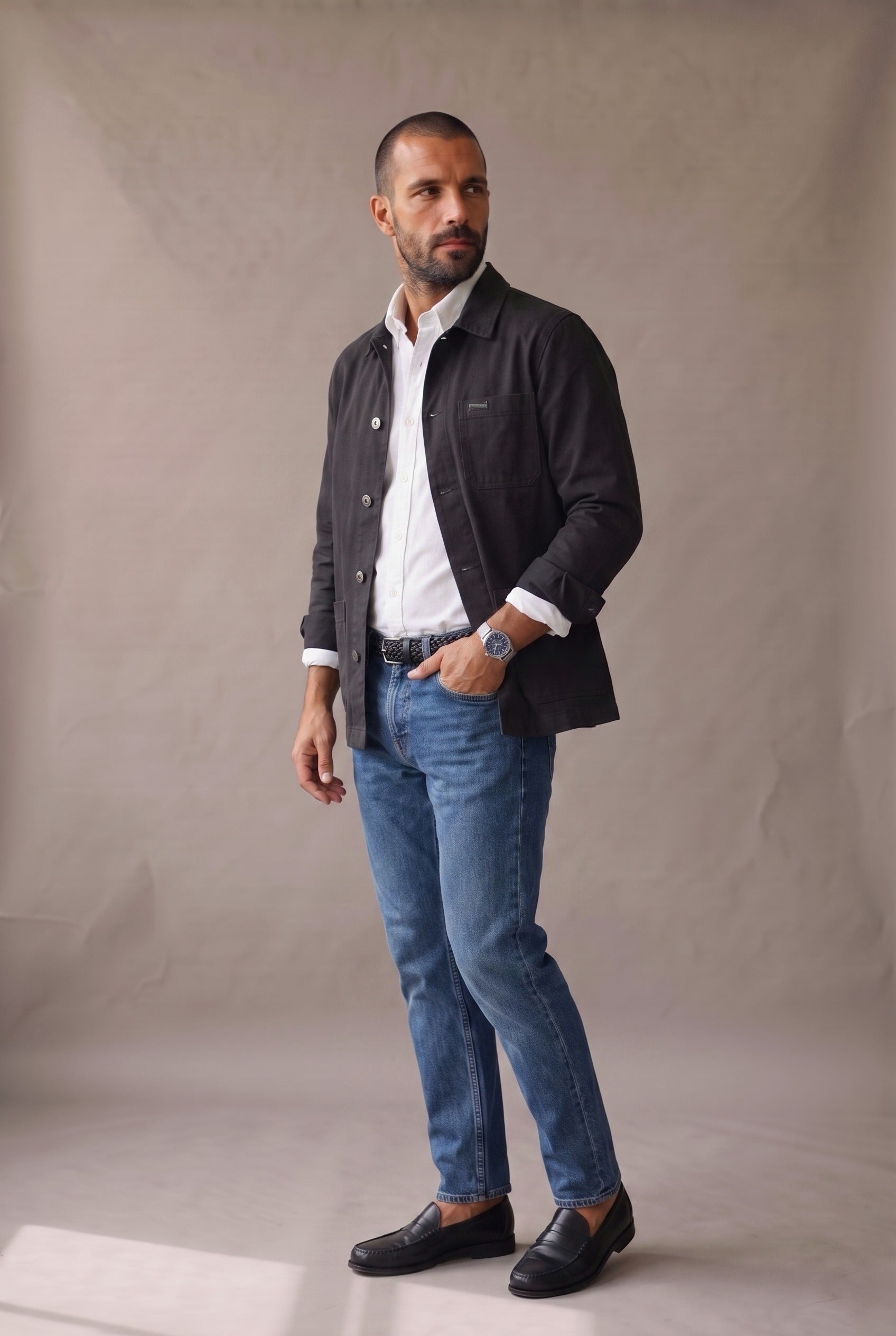 Chaqueta obrera negra para hombre de Luck & Load, vista lateral de cuerpo entero con cinturón de cuero trenzado y mocasines negros.