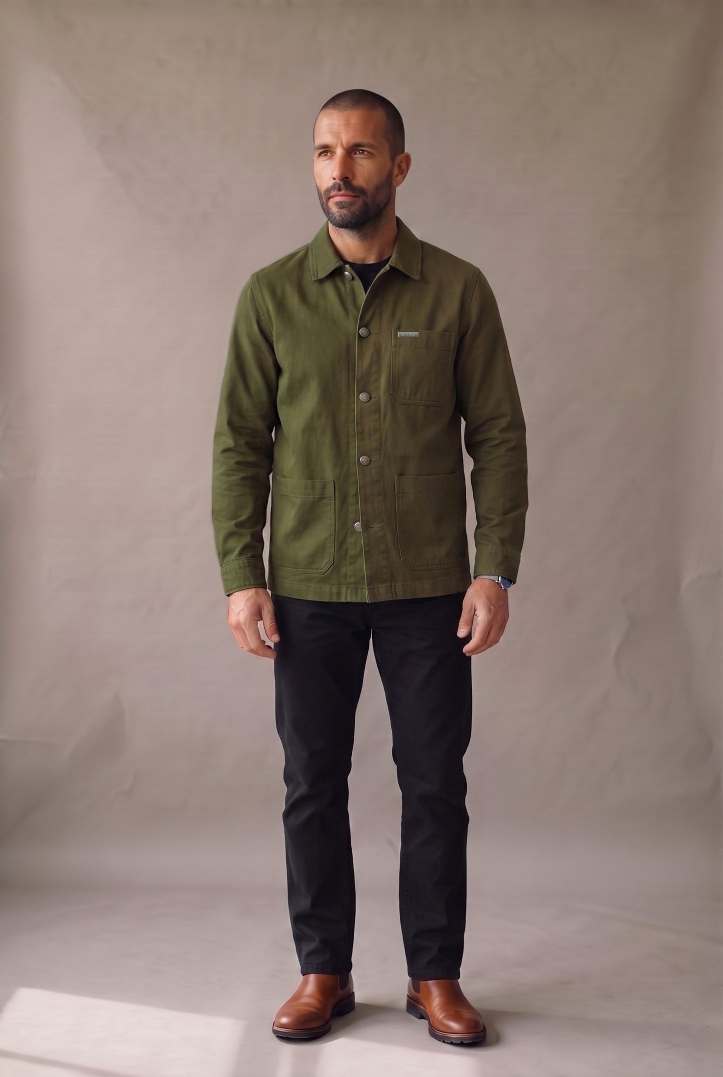Chaqueta obrera verde militar para hombre de Luck & Load, vista frontal con la prenda abotonada sobre jean negro.