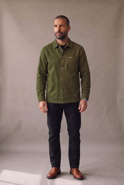 Chaqueta obrera verde militar para hombre de Luck & Load, vista frontal con la prenda abotonada sobre jean negro.